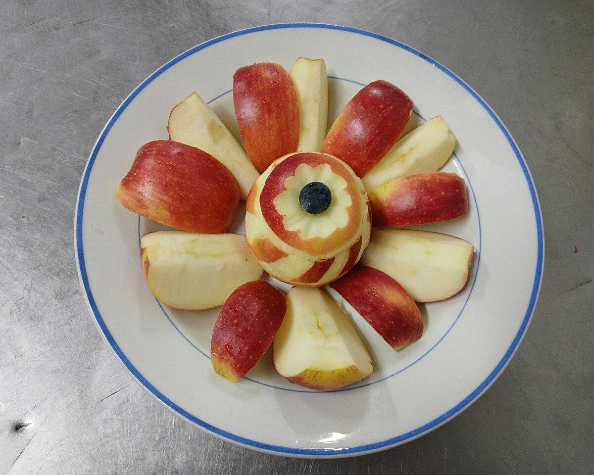 A red apple cut into wedges and arranged on a plate