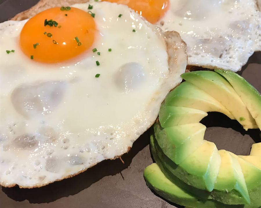 Fried eggs served with sliced avocado