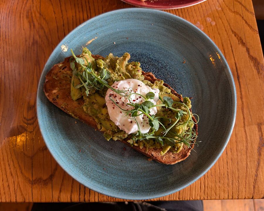 Smashed avocado on toast topped with a poached egg and herbs