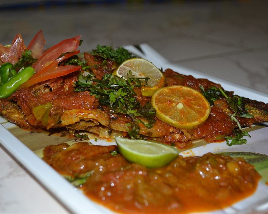 A whole baked fish in tomato sauce with herbs and lime slices