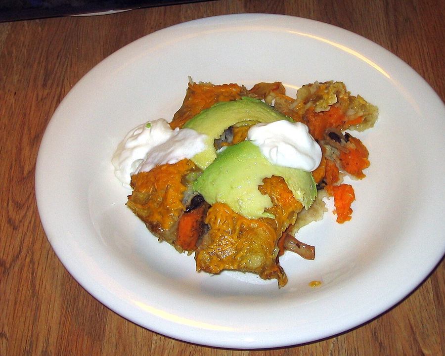 Sweet potato and black bean enchiladas topped with avocado and sour cream