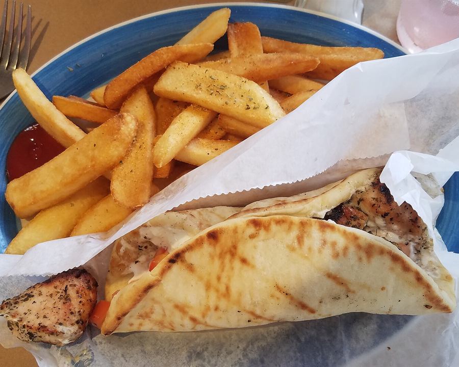 A chicken souvlaki pita with tzatziki and tomato, served with french fries