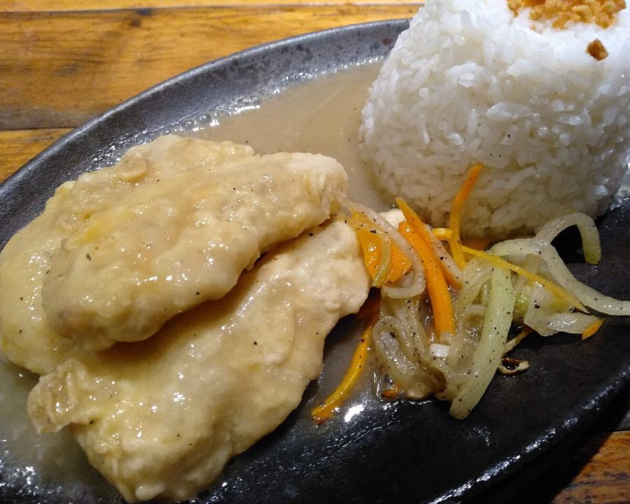 A white fish fillet with rice, carrot and onion on a serving plate