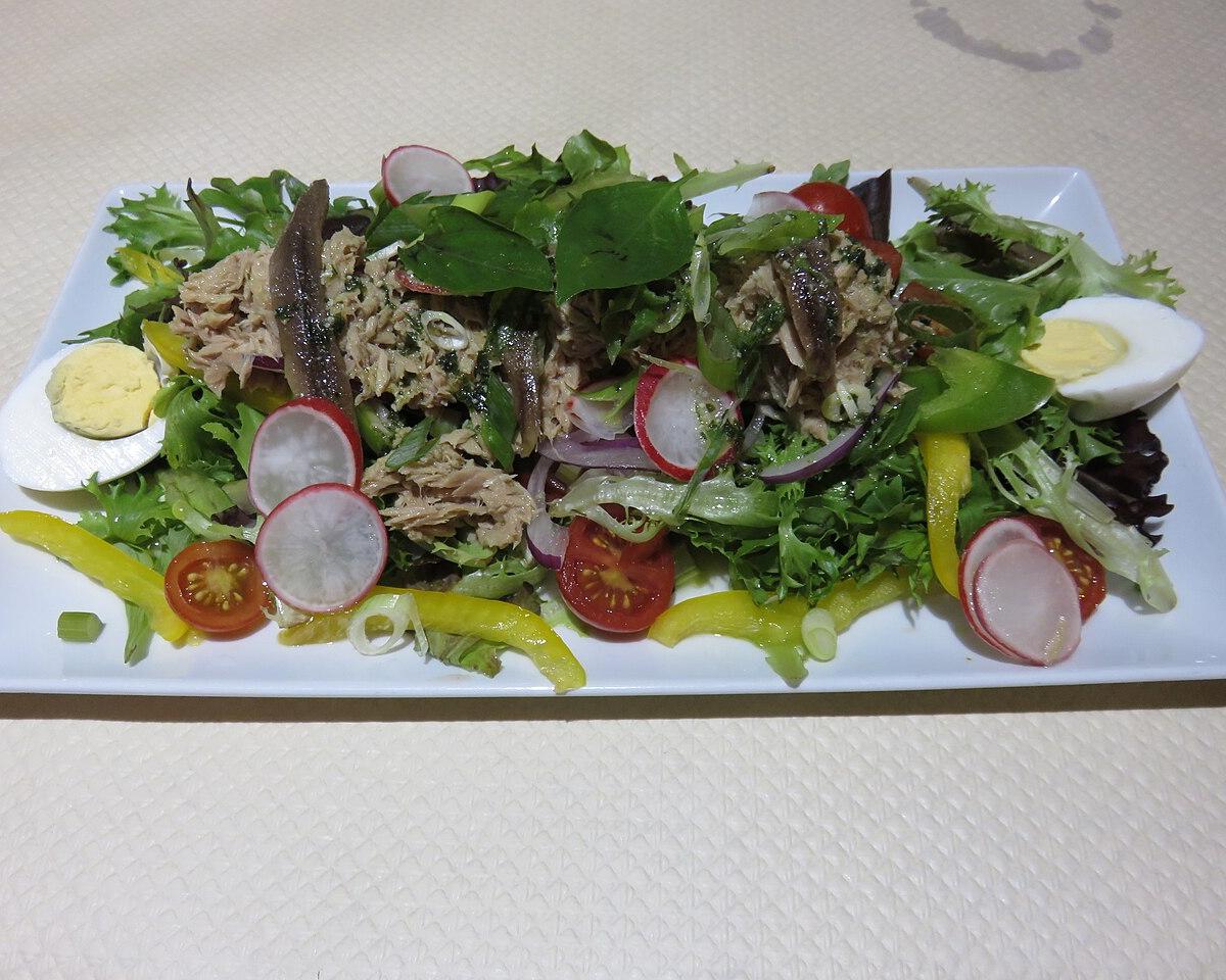 A salade niçoise with tuna, boiled egg, tomato and green leaves