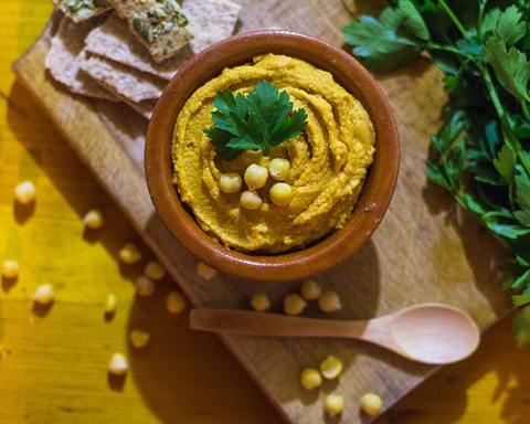 Serving inspiration: A bowl of hummus topped with whole chickpeas and parsley on a wooden board. Not verified as this exact recipe.