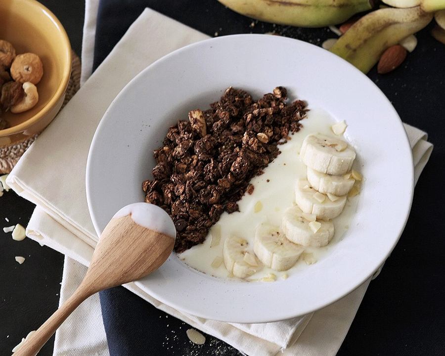 Greek yogurt with sliced banana and granola in a white bowl