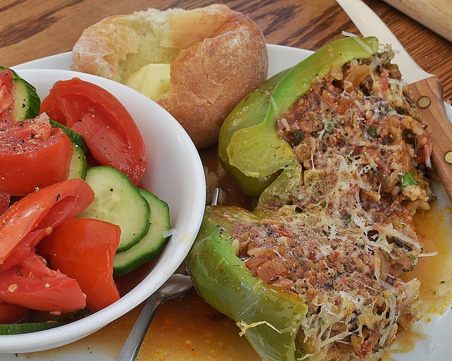 A stuffed green pepper with a savory filling, served with salad and potato