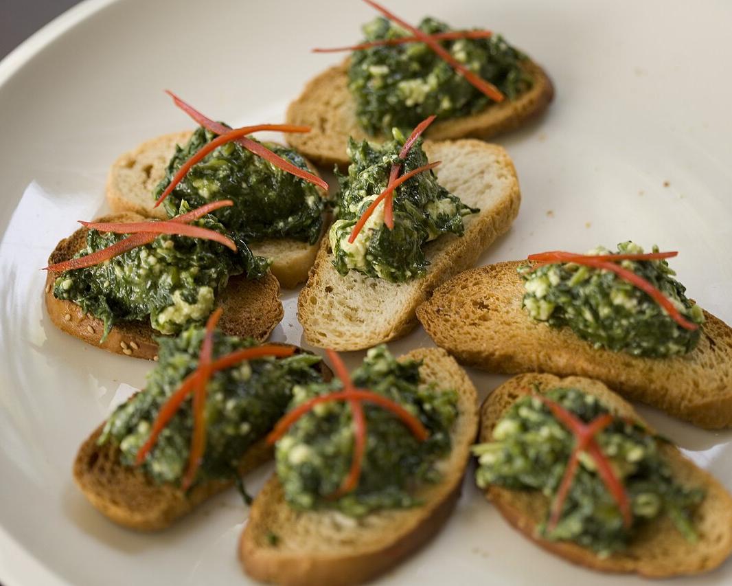 Crostini topped with a green spread and cheese