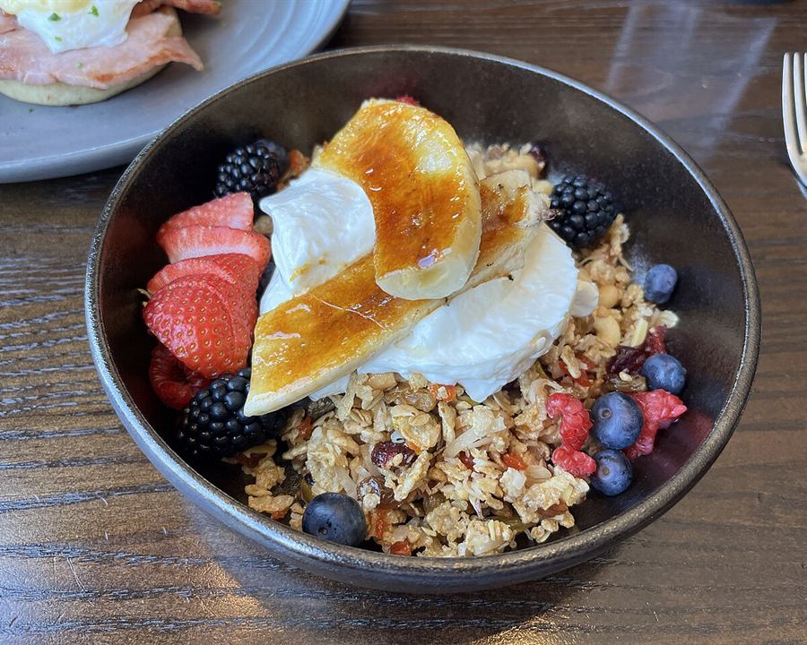 A bowl of yogurt with granola, strawberries, blueberries and caramelized banana