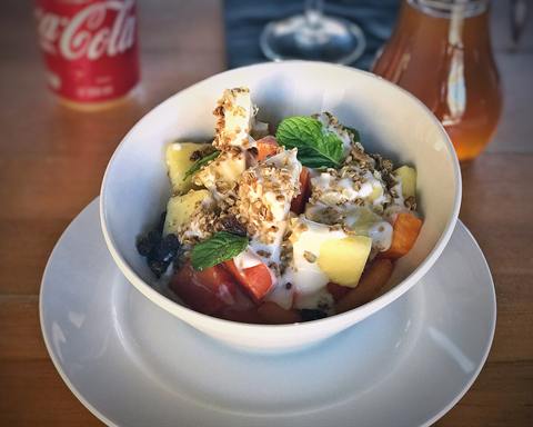 Serving inspiration: A white bowl of yogurt with pieces of fruit, granola and mint. Not verified as this exact recipe.